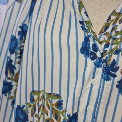 Blusa feminina às riscas azuis com flores azuis e colar azul em manequim