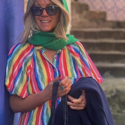 Mulher com vestido listrado colorido, cachecol verde e óculos de sol