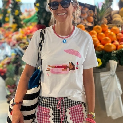 Mulher com t-shirt branca estampada e calças xadrez numa feira de frutas