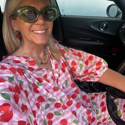Blusa rosa com padrão de cerejas vermelhas usada por mulher dentro de carro