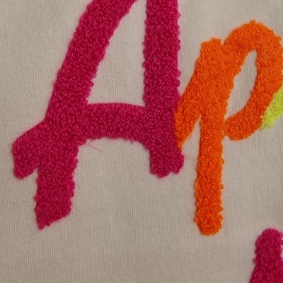 Tecido branco com letras em ponto felpudo rosa e laranja