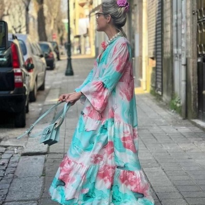 Mulher com vestido comprido azul e rosa floral num passeio urbano