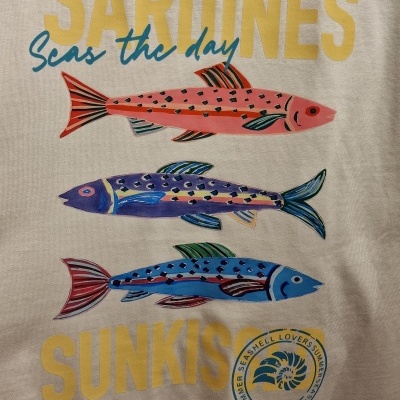 T-shirt bege com estampa de três sardinhas coloridas e texto SARDINES seas the day SUNKISS.