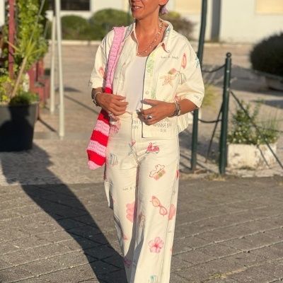 Mulher com conjunto creme estampado e bolsa de crochê em ambiente urbano