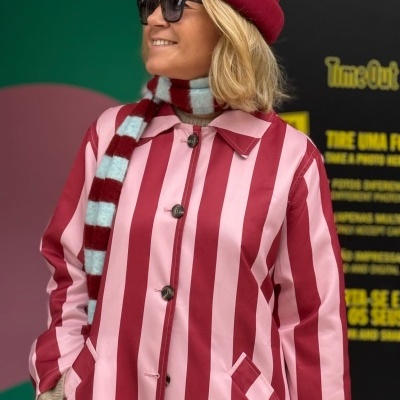 Casaco riscas rosa e vermelho com botões pretos e gola clássica.