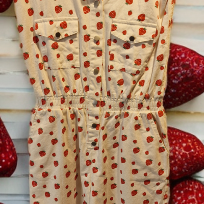Vestido bege curto com padrão de morangos vermelhos em cabide de madeira