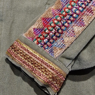 Manga de roupa cinza com bordado colorido e detalhes dourados