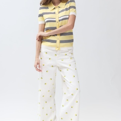 Pessoa com camisa às riscas amarelas e calças brancas com padrão amarelo