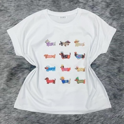 T-shirt branca com estampado colorido de cães dachshund em diferentes roupas e acessórios sobre fundo cinzento.