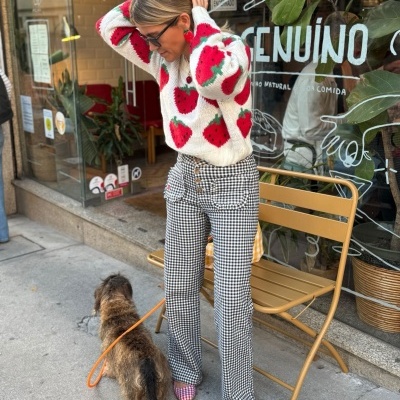Mulher com camisola de morangos e calças xadrez com cão na rua