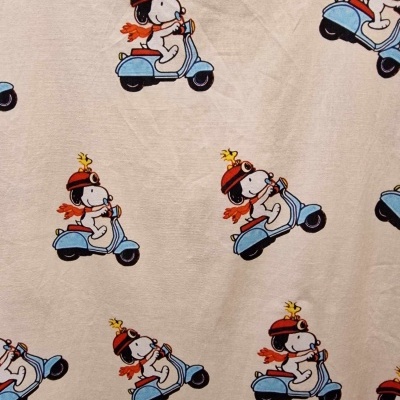 Tecido bege com padrão Snoopy numa scooter azul com capacete vermelho