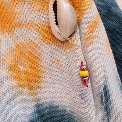 tecido de malha tie-dye com pendente de concha e contas coloridas