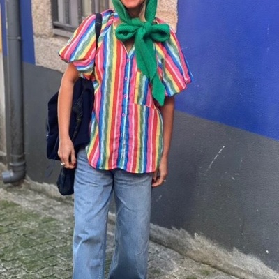 Pessoa com camisa colorida e calças de ganga numa rua