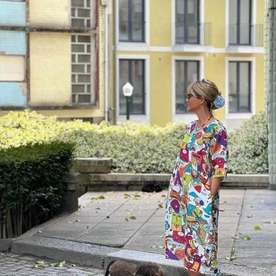 Vestido midi colorido com padrão abstrato em cenário urbano com mulher e cão pequeno