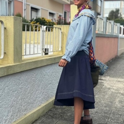 Mulher com roupa azul e sapatos castanhos numa calçada urbana