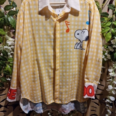 Camisa amarela de manga comprida com padrão xadrez branco e estampa do Snoopy