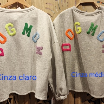 Duas sweatshirts cinza com letras interiores coloridas formando DOG MOM penduradas em cabides de madeira