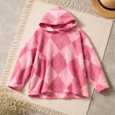 Sweatshirt de capuz rosa e cor de rosa com padrão xadrez em tecido felpudo sobre tapete creme
