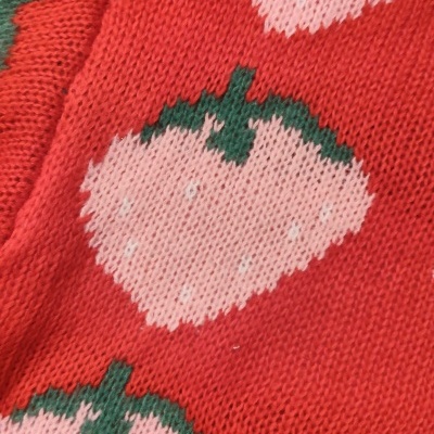 Malha vermelha com padrão de morangos cor-de-rosa e folhas verdes tricotada.