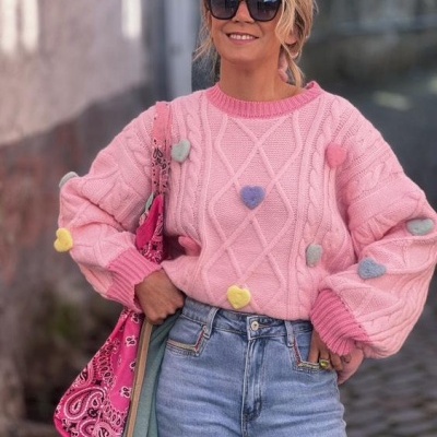 Mulher com camisola rosa com corações e calças de ganga em rua de pedra