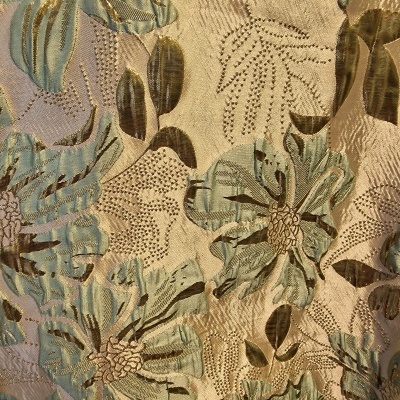 Tecido bordado com padrão floral em azul, verde, castanho e bege.