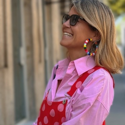 Mulher com brincos de argola coloridos e roupa rosa e vermelha no exterior urbano