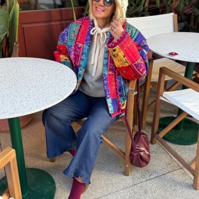 Mulher com casaco colorido sentada numa esplanada