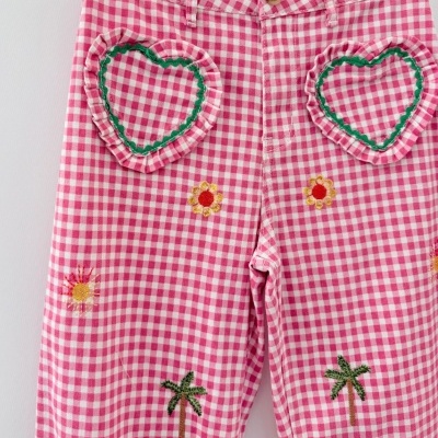 Calças xadrez rosa e branco com bordados coloridos e botão castanho