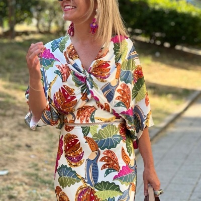 Vestido floral colorido com mangas compridas e decote torcido, mulher com acessórios e bolsa
