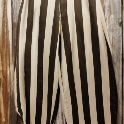 Calças riscas verticais creme e castanho penduradas em cabide