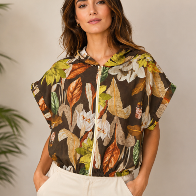 Casaco curto estampado com folhas e flores em tons outonais, com capuz e fecho de correr, usado por mulher.