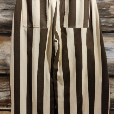 Calças de riscas verticais castanho e bege penduradas em cabide de madeira