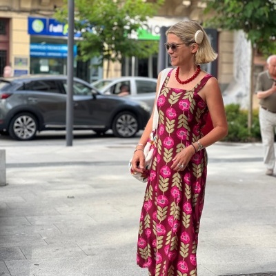 Mulher com vestido floral bordeaux, colar vermelho e sapatilhas rosa ao ar livre
