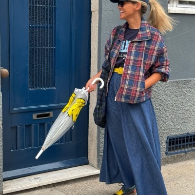 Mulher com roupa casual colorida e guarda-chuva em frente a porta azul