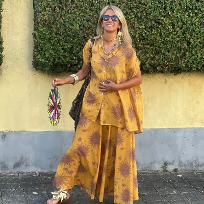Vestido amarelo com flores castanho e sandálias douradas em ambiente exterior