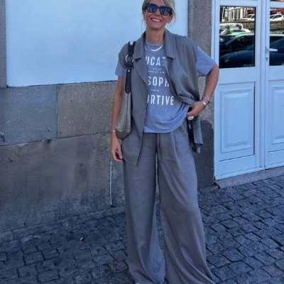 Mulher com roupa cinzenta e sapatilhas brancas numa rua com calçada portuguesa