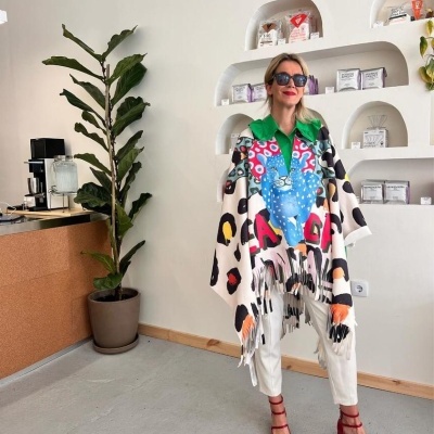 Mulher com poncho colorido em espaço interior com prateleiras e planta