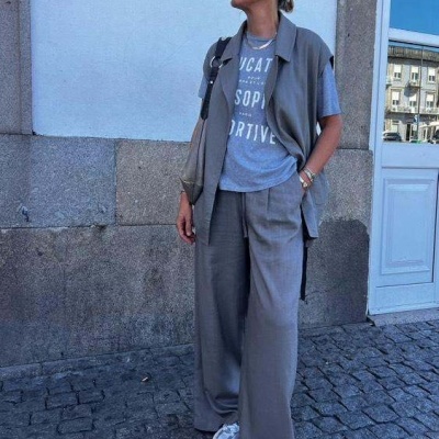 Mulher com roupas cinzentas e camiseta com texto em ambiente urbano