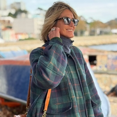 Casaco xadrez verde com mulher usando mala de couro junto à praia