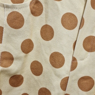 Calças creme com bolas castanhas e bolso frontal