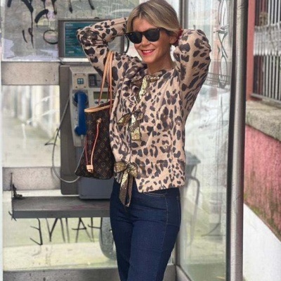Mulher com camisola de padrão animal print e calças jeans num telefone público urbano