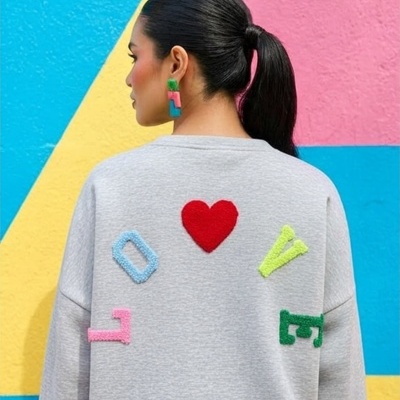 Sweatshirt cinzenta com letras coloridas e coração vermelho vistas pelas costas