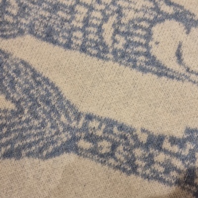 Peça de roupa creme com padrão azul de peixes em tecido de malha