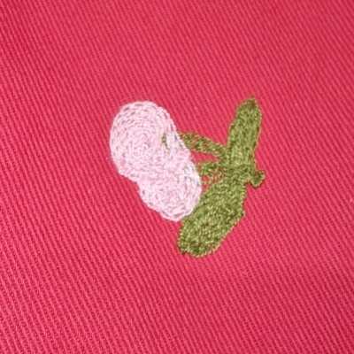 Tecido vermelho com bordado de flores cor-de-rosa e folhas verdes