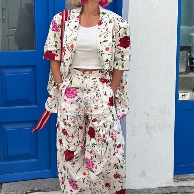 Conjunto floral com blazer e calças largas, top branco, sapatos vermelhos, brincos rosa e óculos de sol pretos
