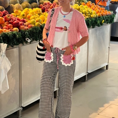 Mulher com roupa colorida e calças xadrez em mercado de frutas