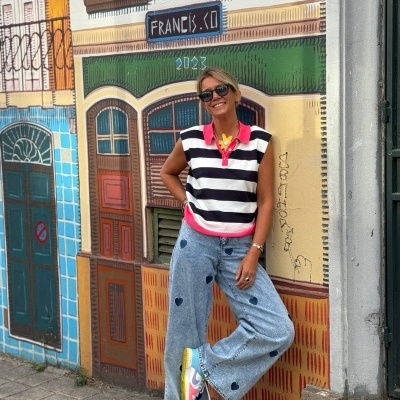 Pessoa com camisola às riscas e calças de ganga com corações junto a mural colorido