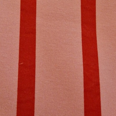 Tecido com riscas verticais largas em vermelho sobre fundo cor de rosa