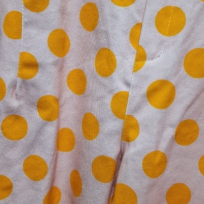Calças rosa claro com bolinhas laranja e botão castanho