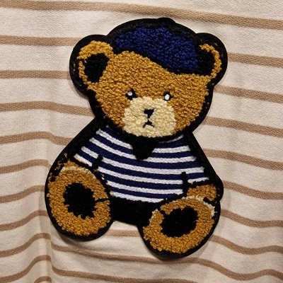 Peça de roupa bege às riscas com aplique felpudo de urso vestido à marinheiro